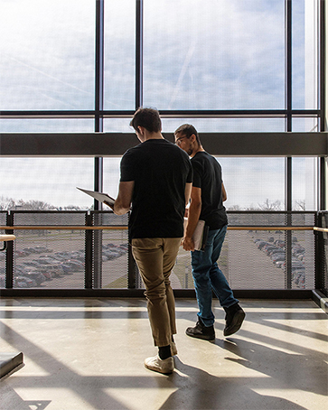 Two students walk together down a hallway, their backs are to the camera