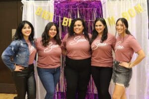 Five women stand together in matching pink shirts that read "Selenas"