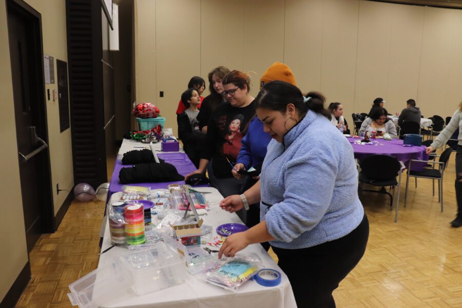 Students pick up craft supplies from a table