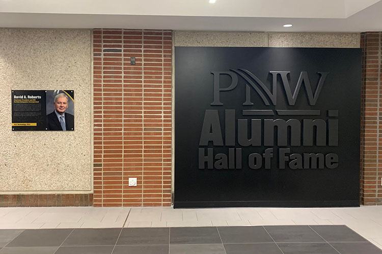 The Alumni Hall of Fame wall in PNW's SULB building. Inductee David Roberts is featured.