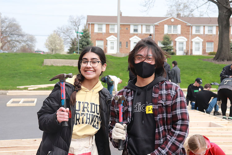 Two honors college students pose while holding up hammers