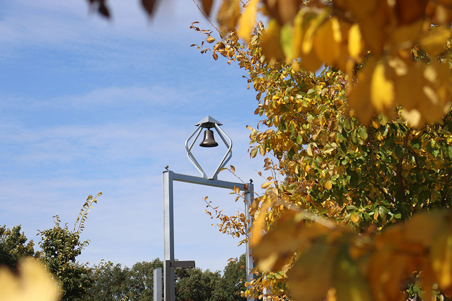 The bell tower is pictured and framed by yellow leaves on the right.