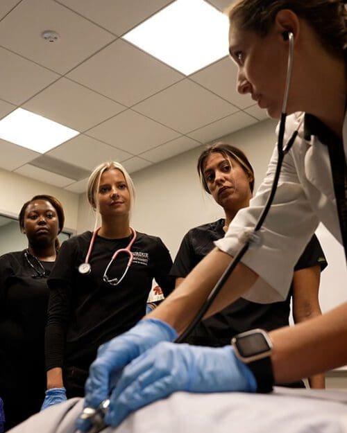 Three nursing students look at their instructor