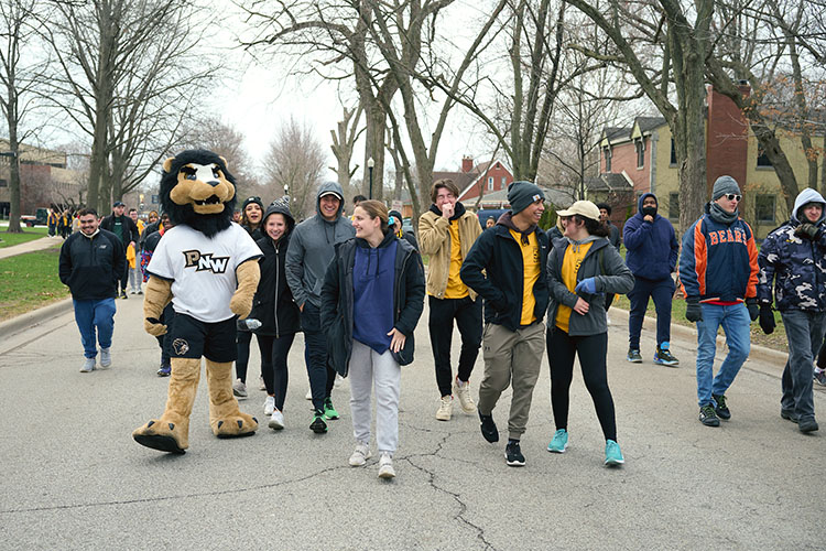 PNW students walk down the street with mascot Leo.