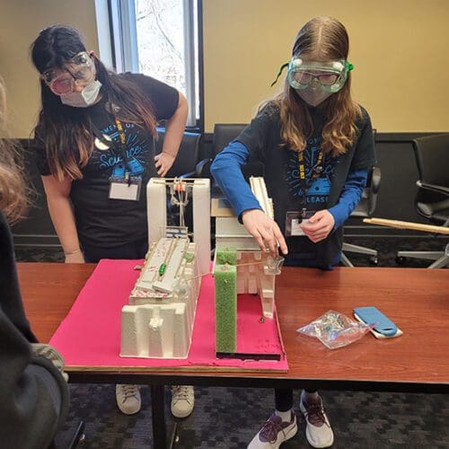 Two students work on a Science Olympiad model