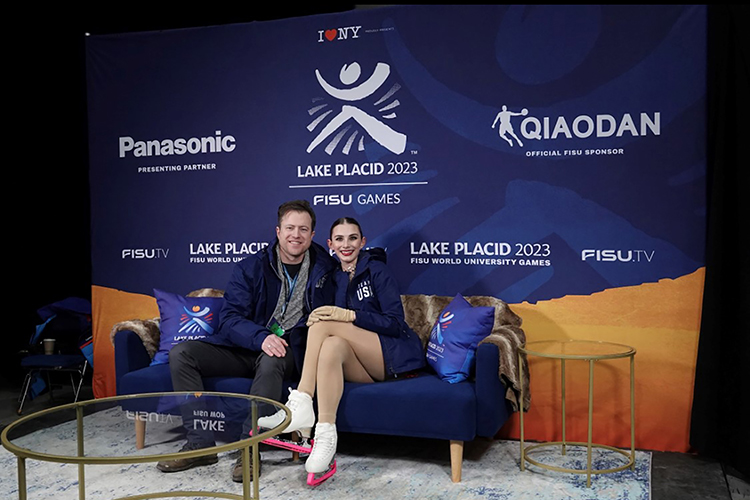 Finley Hawk and her coach sit on a couch and pose in front of a backdrop