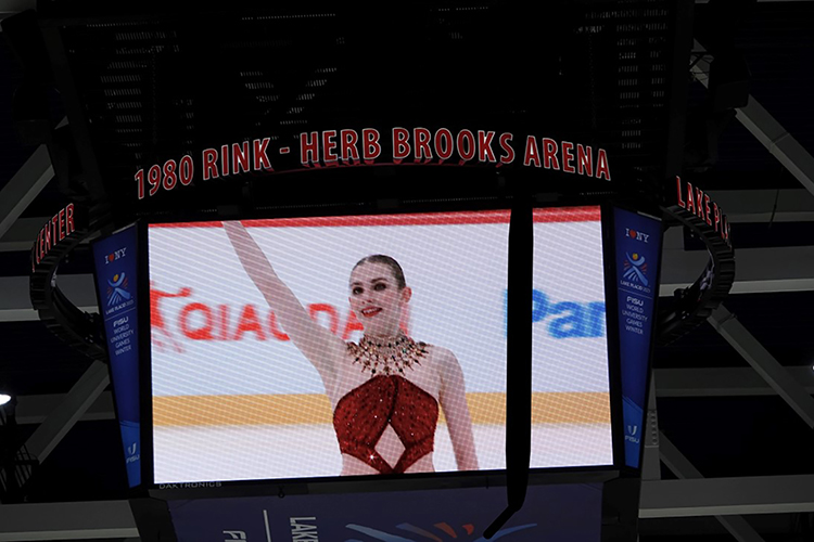 A screen shows a close-up live feed of Finley Hawk waving while standing on the ice.