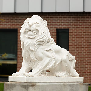 PNW Lion Statue with a brick wall in the background