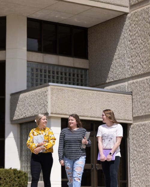 Three students walk together outside.