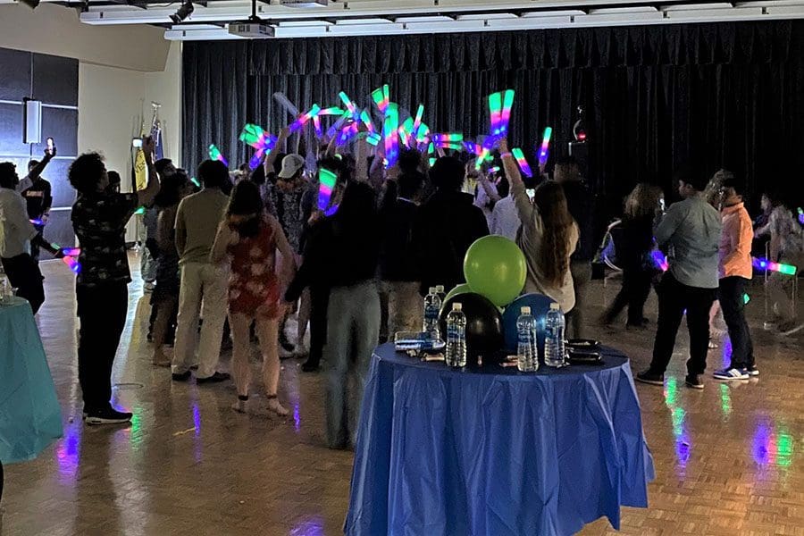 Students hold up glow sticks while they are in a crowd