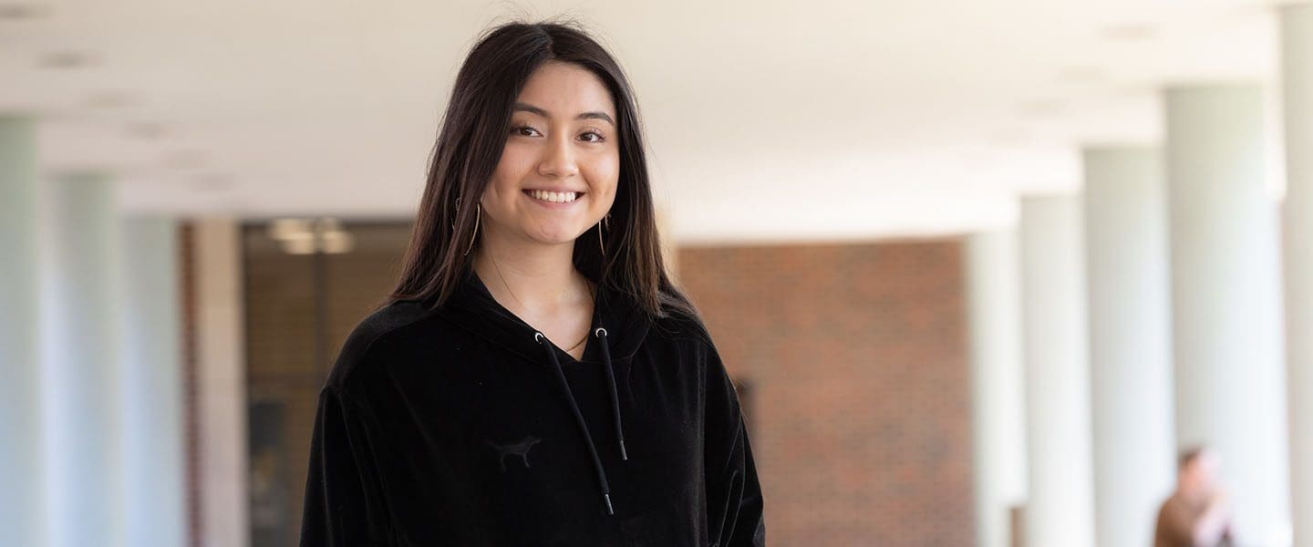 A PNW student by the Student Union and Library Building