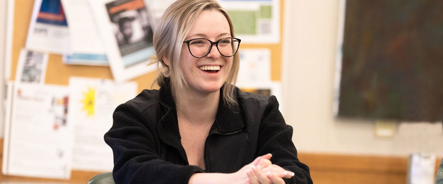 A young woman in glasses laughs in the classroom