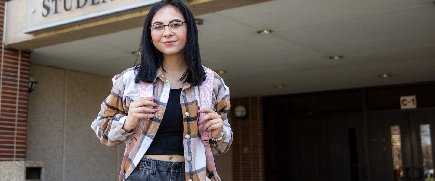 A Human Development and Family Studies major stands outside the Student Union and Library building