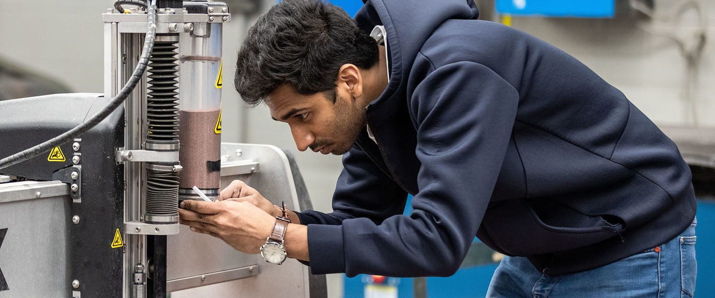 A technology student adjusts industrial machinery.