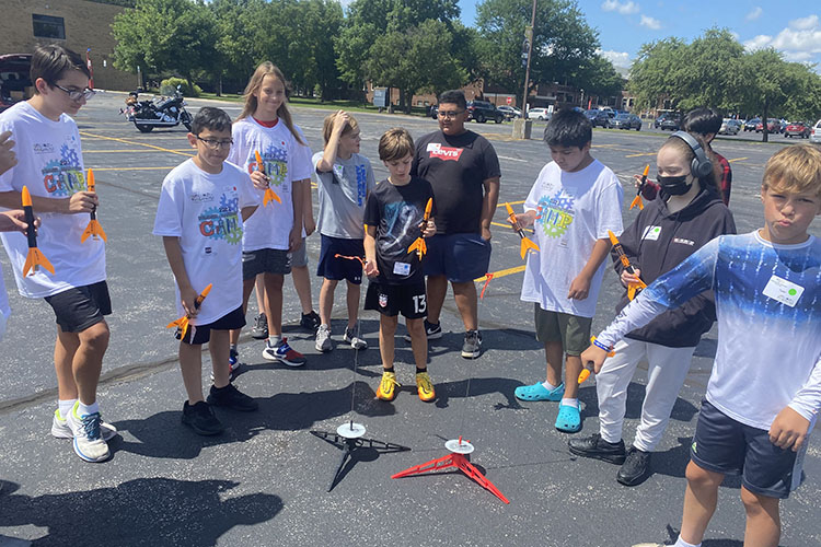 PNW camp participants get ready to launch rockets in a parking lot.