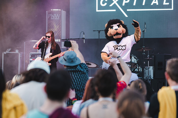 PNW's mascot, Leo, joins the band Cxpital onstage during their performance.
