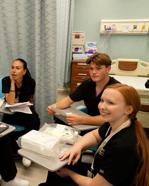 Three nursing students sit in a lab room