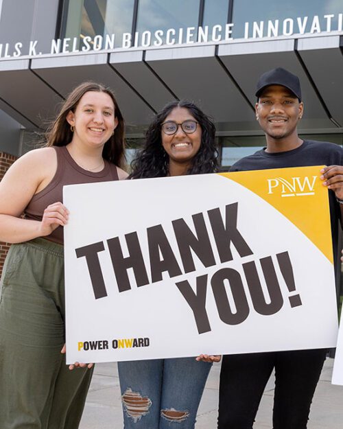 PNW students holding a "thank you" sign in front of the Nils K. Nelson Bioscience Innovation Building