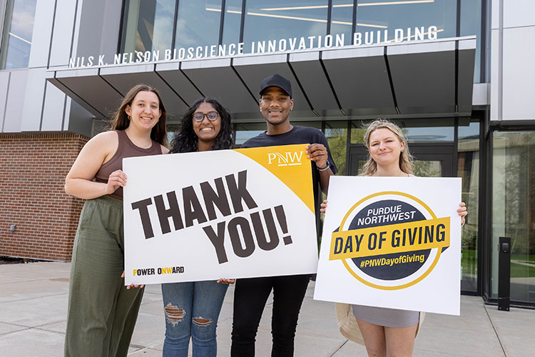PNW students holding a "thank you" sign in front of the Nils K. Nelson Bioscience Innovation Building