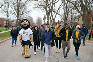 A group of people walk with Leo the lion during the honors 5k