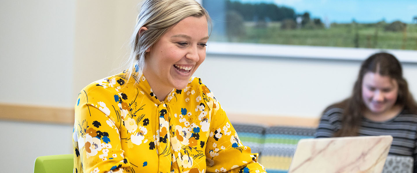 A PNW student works on her laptop in a conference room