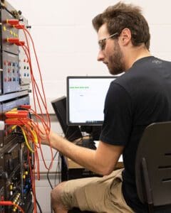 A student plugs wires into a box