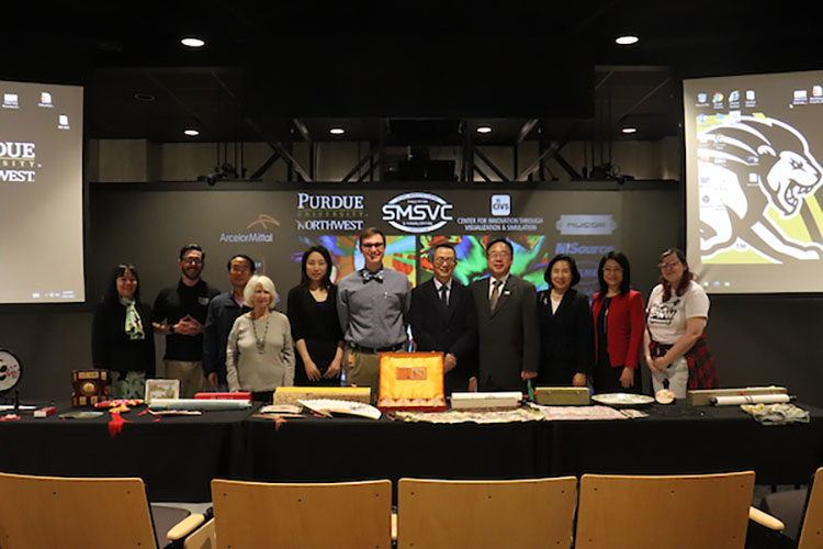 A group of people stand together behind a display of Asian Art in America