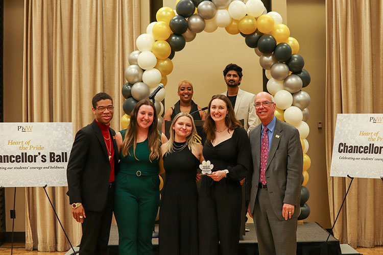 Six students and Chancellor Keon pose under a balloon arch during the Chancellor's ball