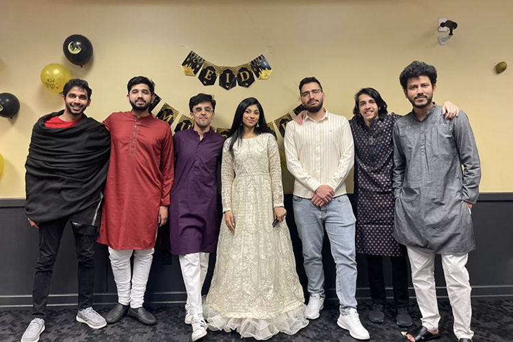 Seven students pose together in front of Eid decorations