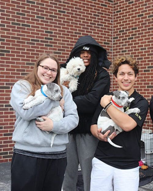 PNW students pose while holding small dogs.