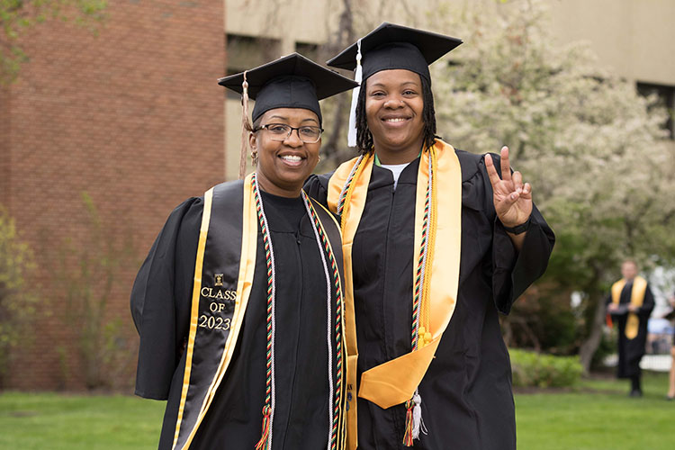 Two PNW graduates in caps and gowns pose together