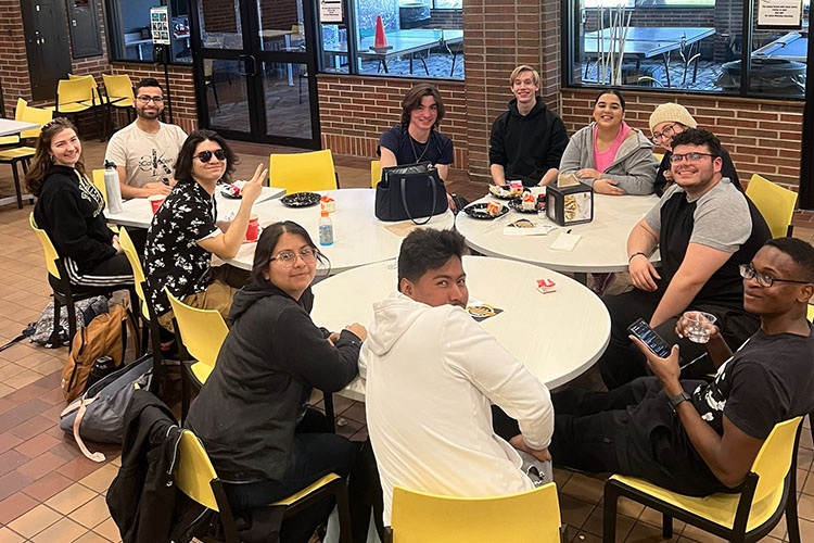 Students sit at several round tables that were pushed together.