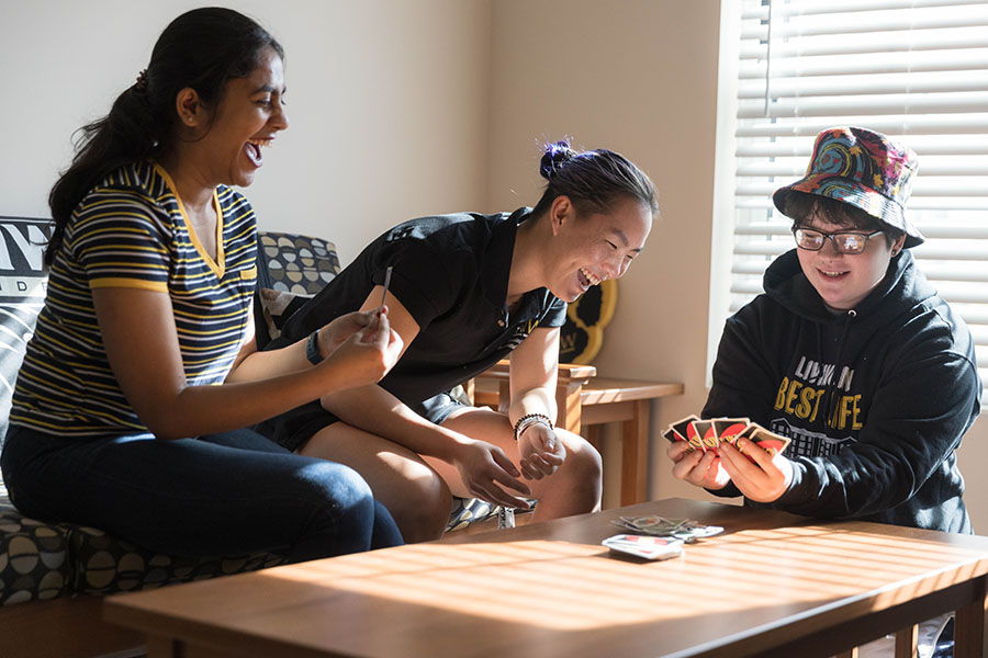 Three students sit around a coffee table in a University Village dorm room