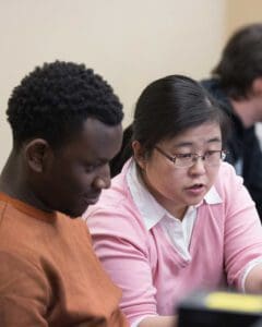 Two students sit and work on a computer during class