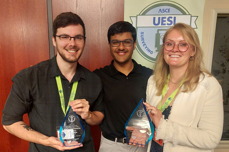 Three students pose with trophies