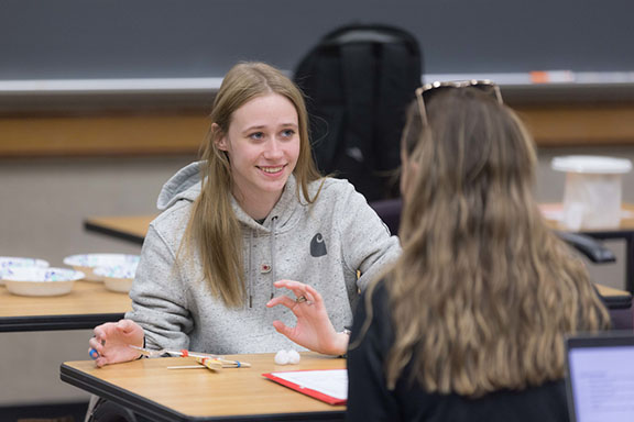 A student sits at a wooden table.