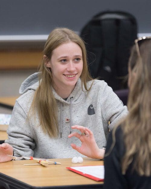 A student sits at a wooden table.