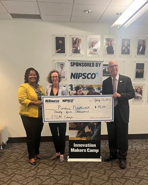 Three people stand with a large check. Left to right: Alexius Barber, Rachel Clapp-Smith, and PNW Chancellor Thomas L. Keon.