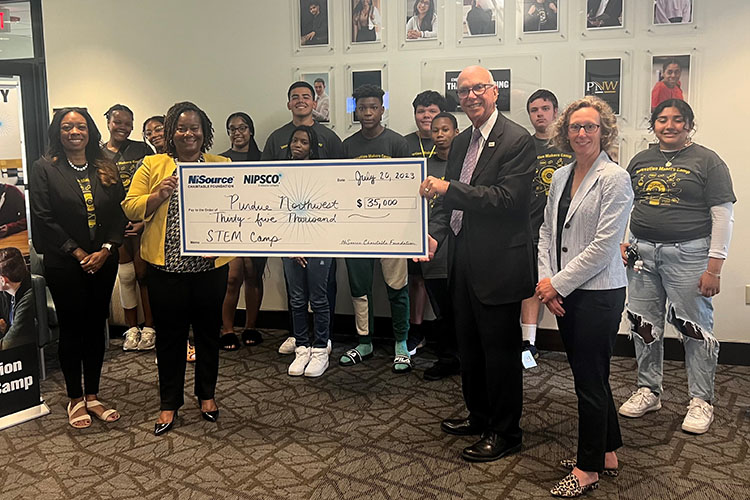 A group of people stand behind a large check