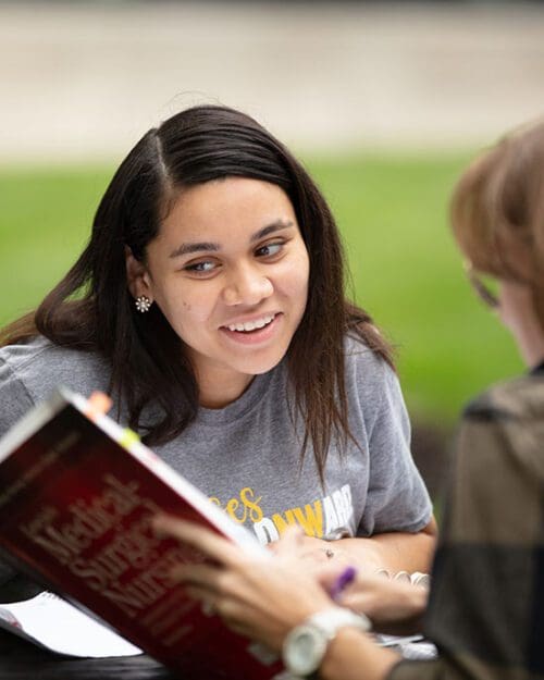 A PNW student reads a textbook outdoors