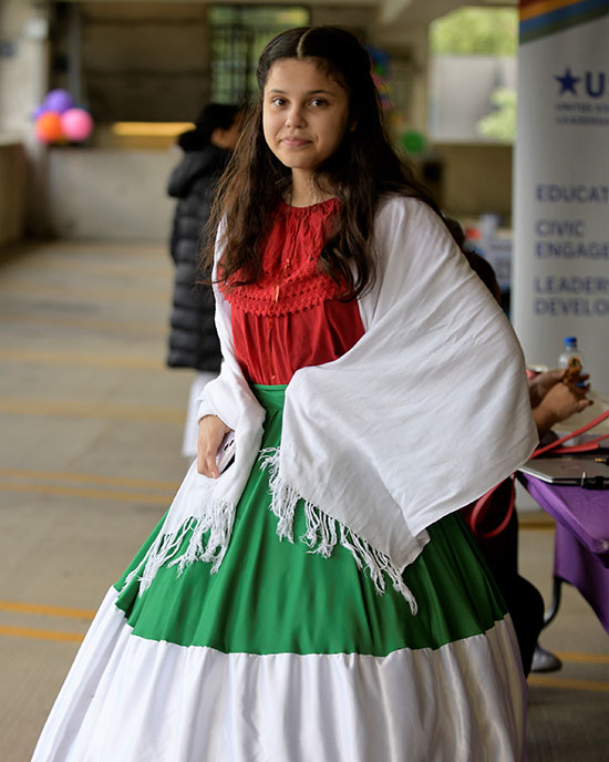 A person stands in a dress that mirrors the Mexican flag