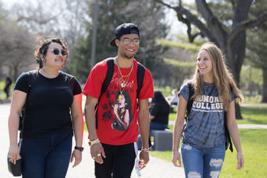 Three students walk together on campus