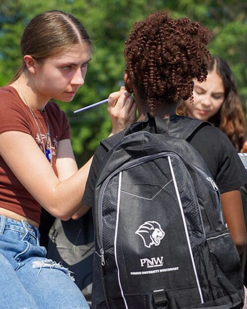 A girl gets her face painted at PNW's backpack giveaway.