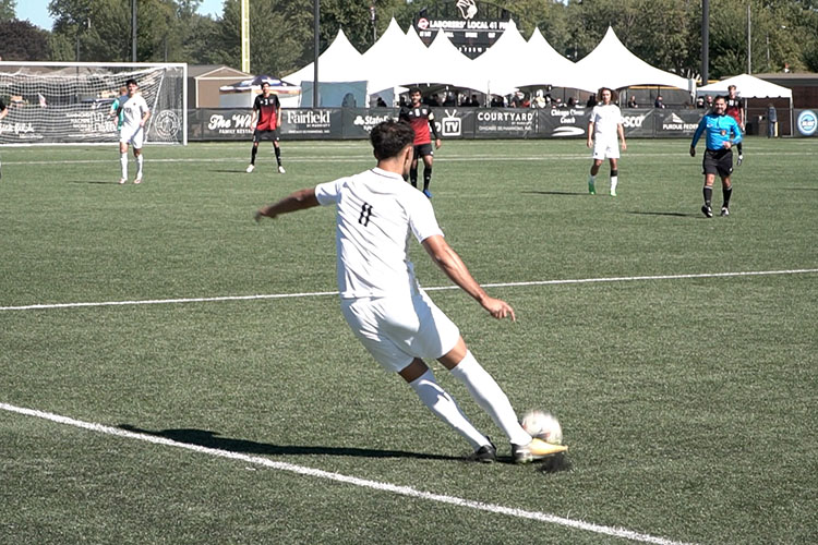 A PNW men's soccer player kicks a ball