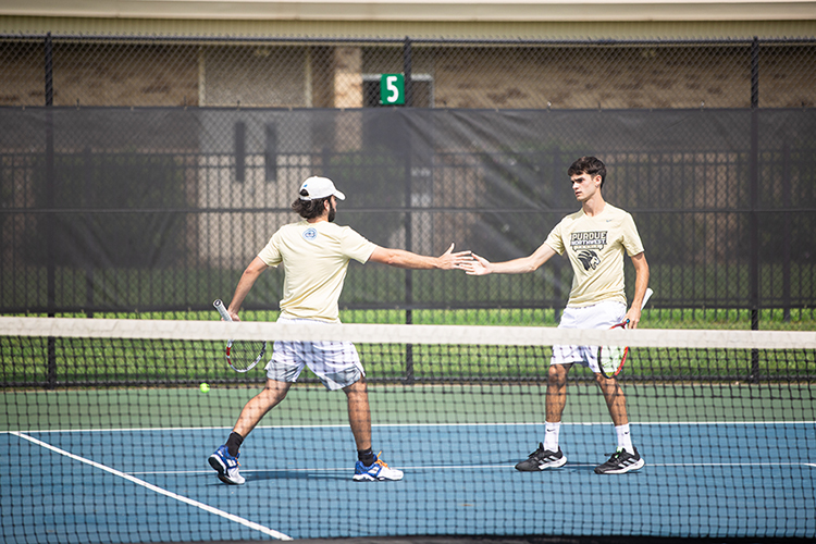 Two PNW men's tennis players high five on the court