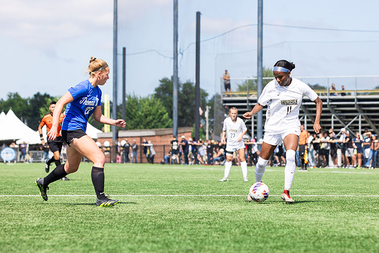 Two women's soccer players are pictured mid-game. The PNW player has the ball.