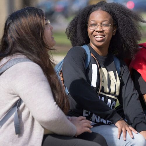 Students sit on a bench and talk.