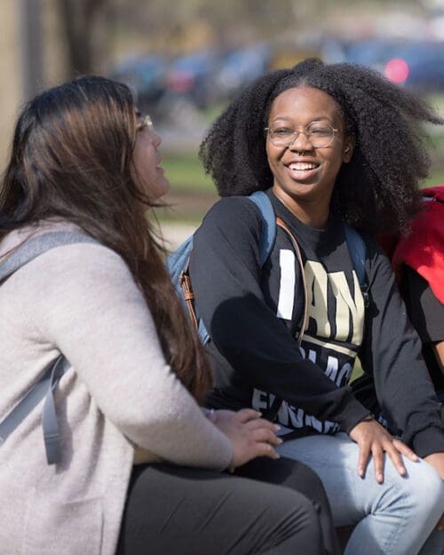 Students sit on a bench and talk.