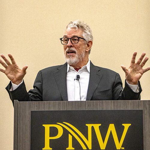 Bruce Perry stands behind a podium that has the PNW logo on it