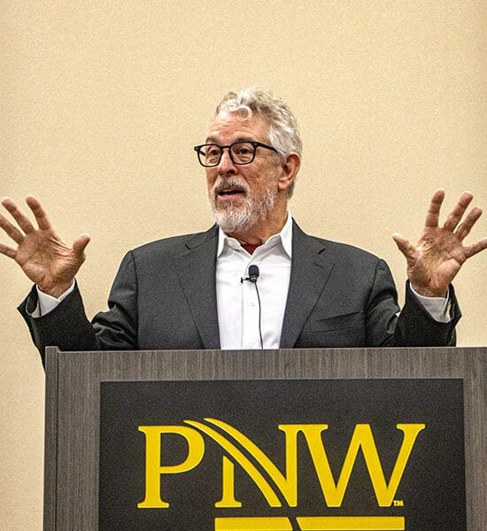 Bruce Perry stands behind a podium that has the PNW logo on it